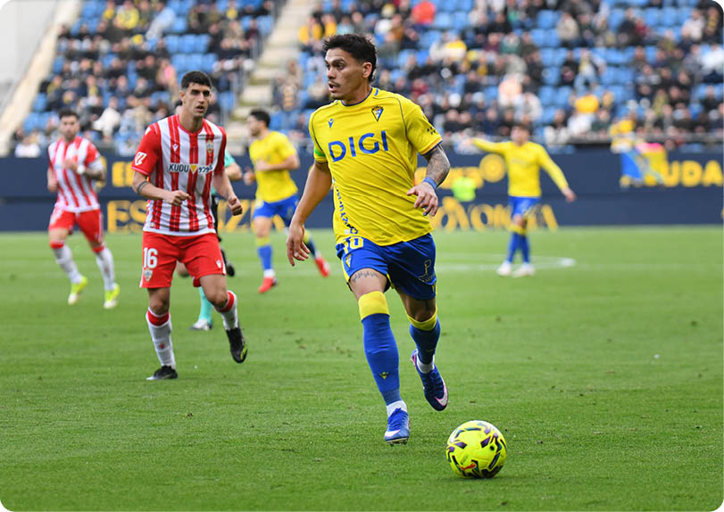 A soccer player in a yellow and blue uniform is running with the ball. Contenido generado con IA