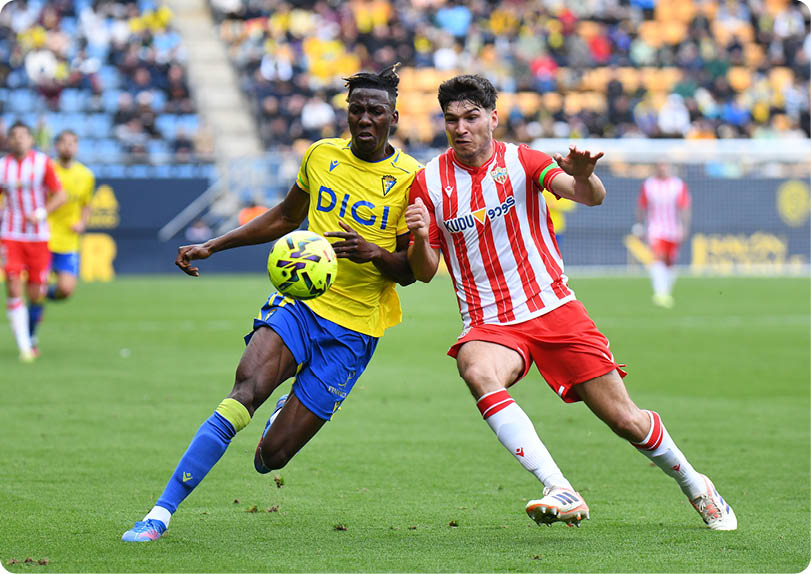 Two soccer players are competing for the ball on the field. Contenido generado con IA