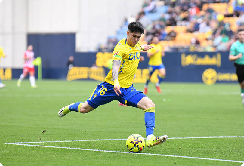 A soccer player in a blue uniform is kicking a yellow ball on a field. Contenido generado con IA