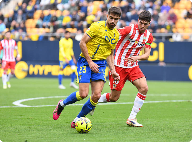 Two soccer players from opposing teams are fighting for control of the ball. Contenido generado con IA