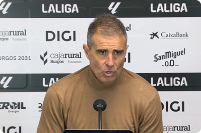 A man wearing a brown shirt is speaking into a microphone. Contenido generado con IA