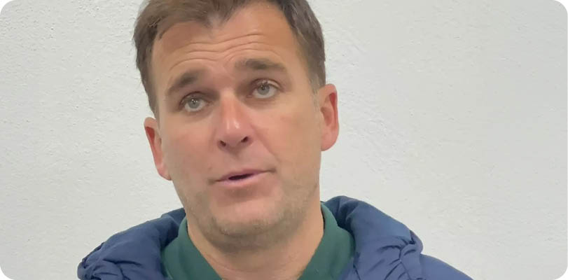 A man wearing a blue jacket and a green shirt is being interviewed by a reporter. Contenido generado con IA