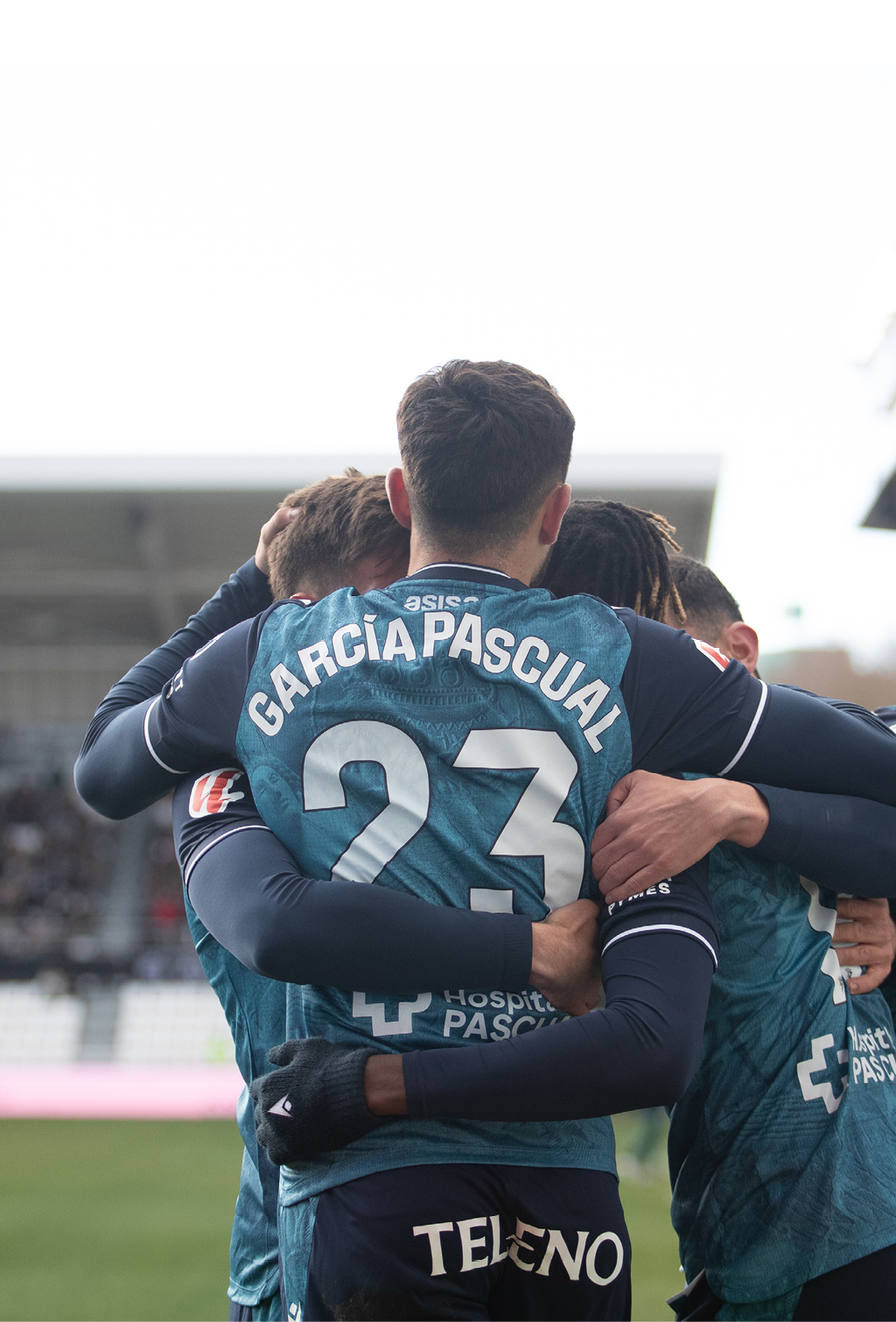 Four soccer players hugging each other on the field. Contenido generado con IA