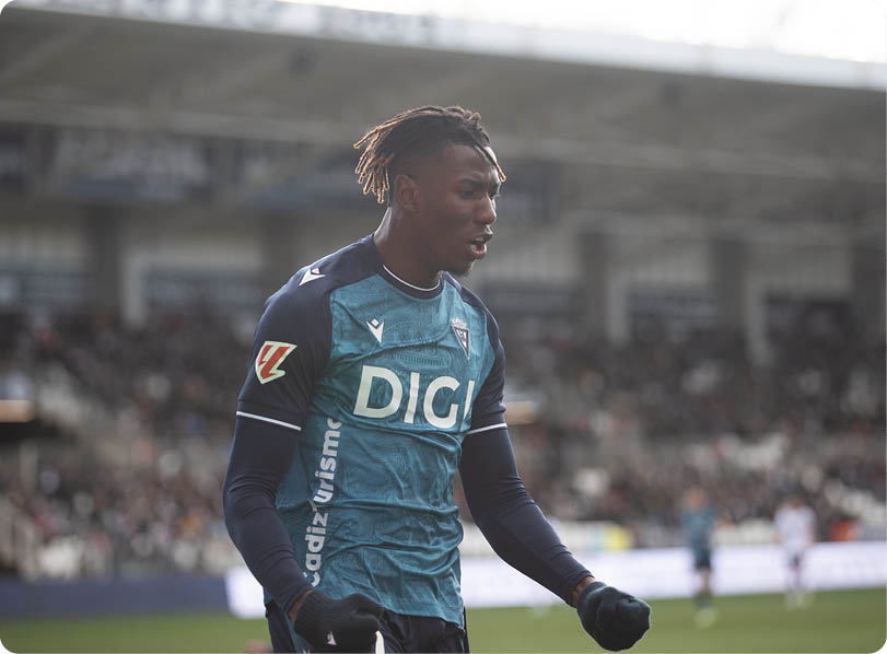 A soccer player in a blue and white uniform stands on the field. Contenido generado con IA