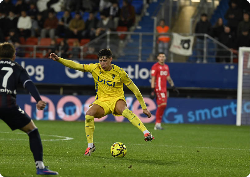 Two soccer players are on the field, one is kicking the ball and the other is trying to block it. Contenido generado con IA