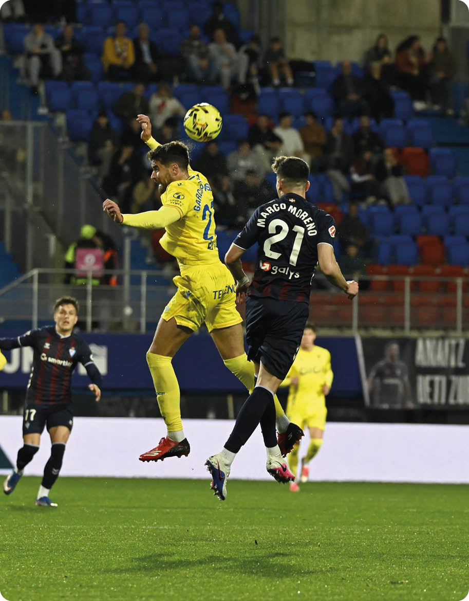 Soccer players on a field, one player is jumping in the air to kick the ball. Contenido generado con IA