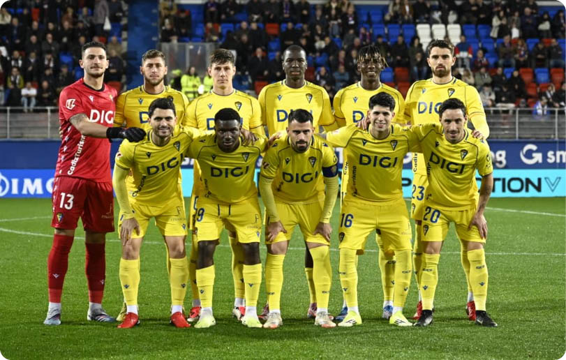 A group of soccer players in yellow and red uniforms pose for a picture on the field. Contenido generado con IA