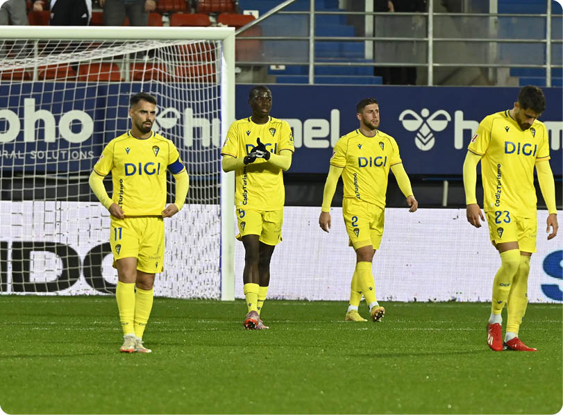 Four soccer players wearing yellow uniforms are standing on the field. Contenido generado con IA