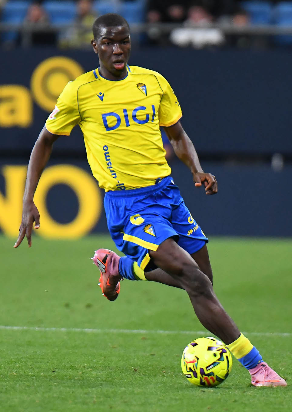 A soccer player in a yellow and blue uniform is about to kick a soccer ball. Contenido generado con IA