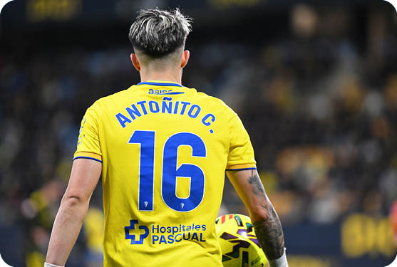 A soccer player wearing a yellow jersey with the number 16 on the back. Contenido generado con IA