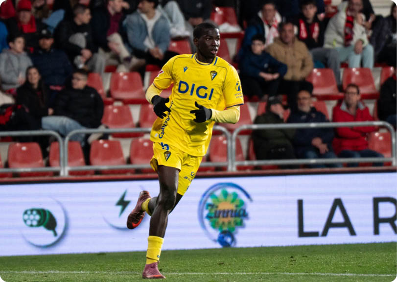 A soccer player in a yellow jersey is running on the field. Contenido generado con IA