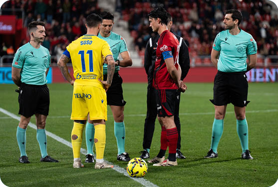 A group of men in uniforms are standing on a field, engaged in conversation. Contenido generado con IA