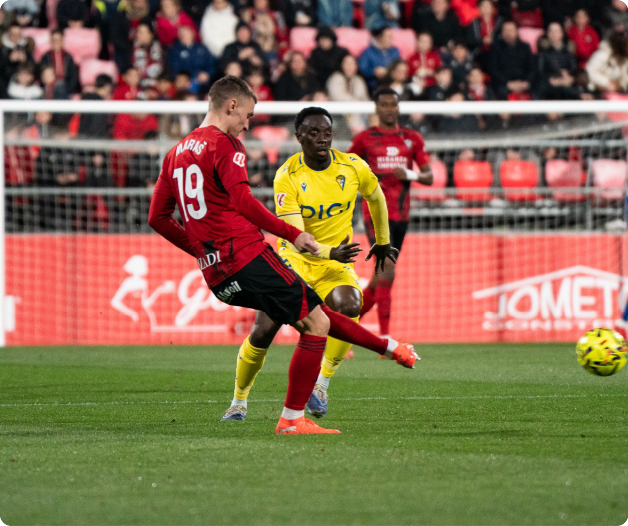 Soccer players on a field, one kicking the ball. Contenido generado con IA