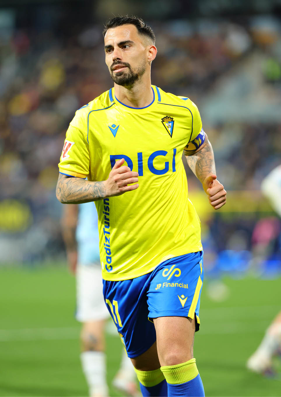 Two soccer players are on the field, one in a yellow shirt and the other in a red shirt. The yellow player is about to kick the ball. Contenido generado con IA