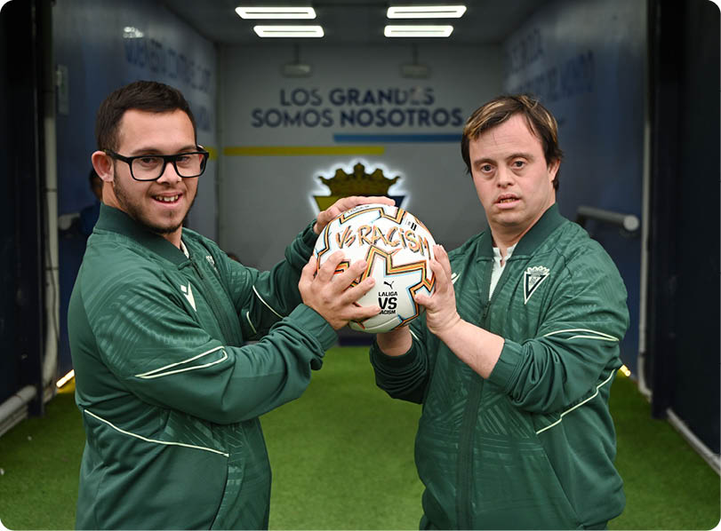 A soccer player in a yellow jersey is running on the field, smiling and pointing. Contenido generado con IA