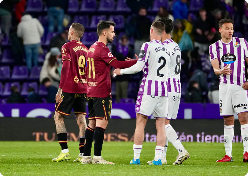 Two soccer players shake hands on the field. Descripci n generada con IA