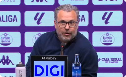 A man in a blue shirt sitting in front of a microphone. Descripci n generada con IA