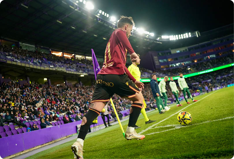 A soccer player wearing a red shirt and black shorts. Descripci n generada con IA