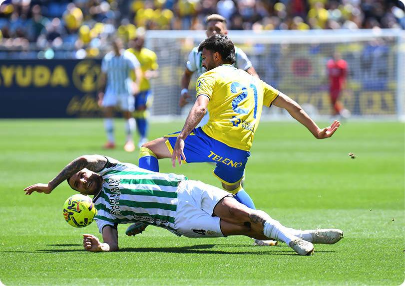 Two soccer players are on the field, one is falling to the ground. Descripci n generada con IA