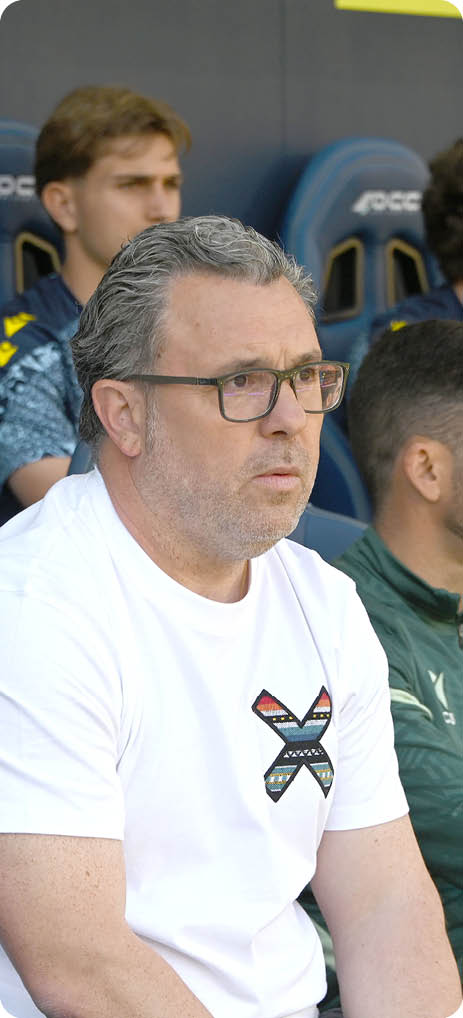 A man wearing glasses sitting in a blue chair. Descripci n generada con IA