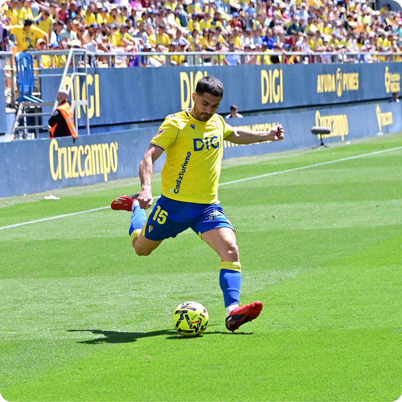 A soccer player in a yellow and blue uniform kicks a soccer ball. Descripci n generada con IA