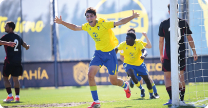 A man wearing a yellow and blue soccer uniform is running towards a goal. Descripci n generada con IA
