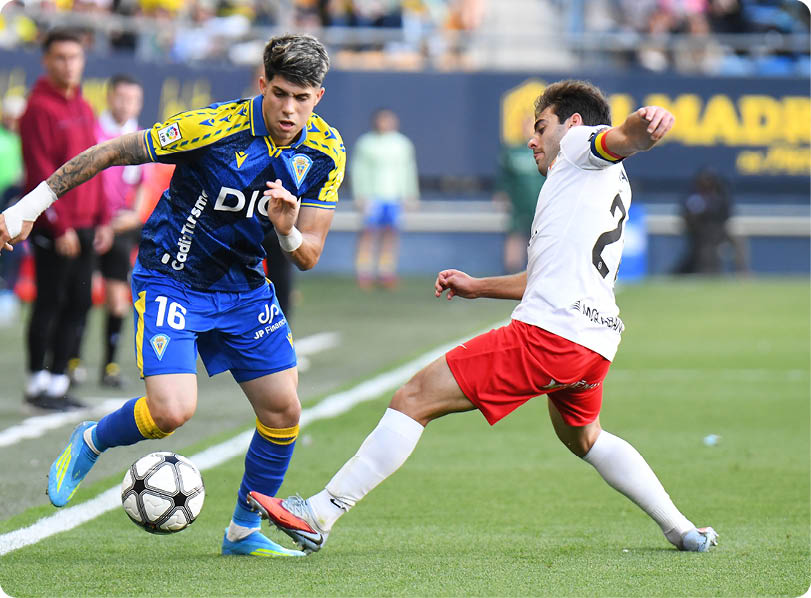 Two soccer players are playing on a field. Descripci n generada con IA