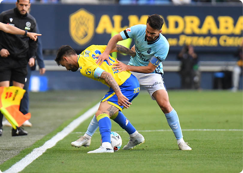 Two soccer players are fighting for the ball. Descripci n generada con IA
