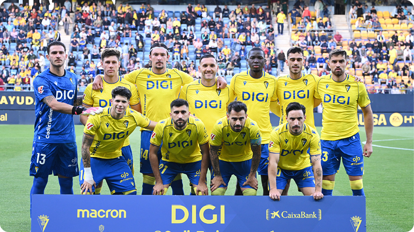 A group of men in yellow and blue shirts pose for a picture. Descripci n generada con IA