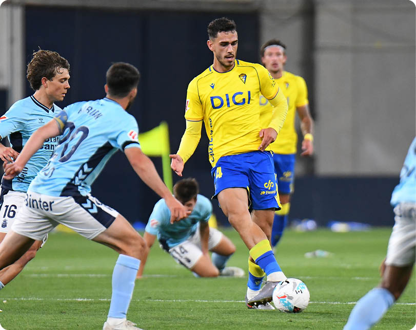 A soccer player in a yellow and blue uniform is kicking a soccer ball. Descripci n generada con IA