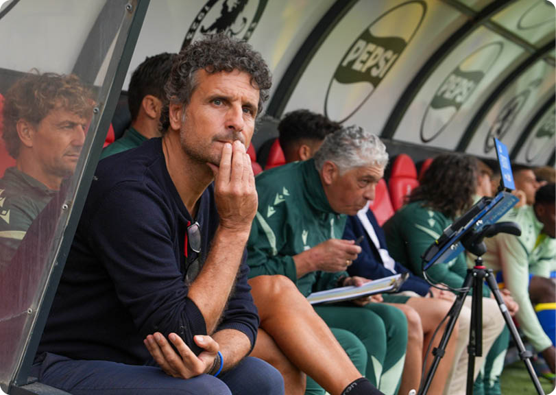 A man with a blue wristband sits on a bench. Descripci n generada con IA