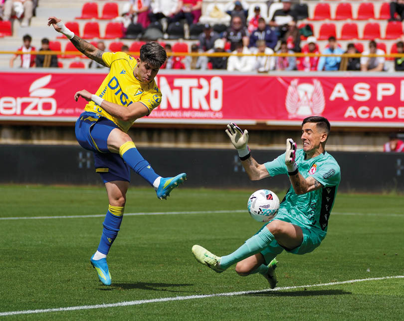 A soccer player in a yellow and blue uniform kicks a soccer ball. Descripci n generada con IA