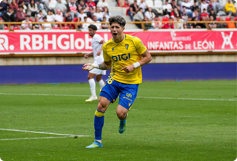 A soccer player in a yellow and blue uniform is running on the field. Descripci n generada con IA