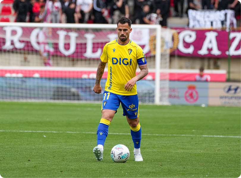 A soccer player in a yellow and blue uniform is about to kick a soccer ball. Descripci n generada con IA