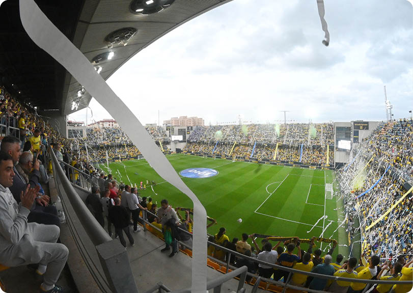 A soccer stadium with a crowd of people watching a game. Descripci n generada con IA