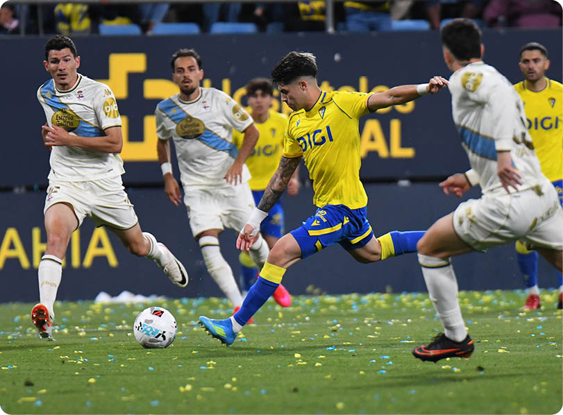 A soccer player in a yellow and blue uniform kicks a soccer ball. Descripci n generada con IA