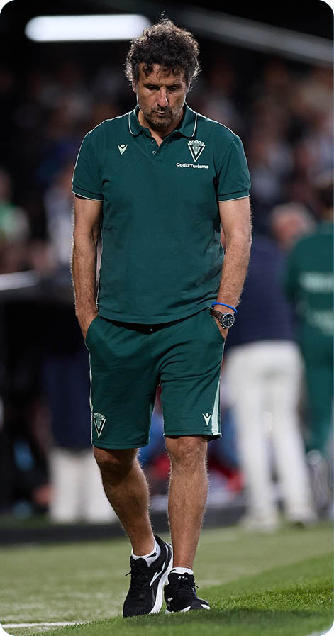 A man wearing a green shirt and shorts is walking on a field. Descripci n generada con IA