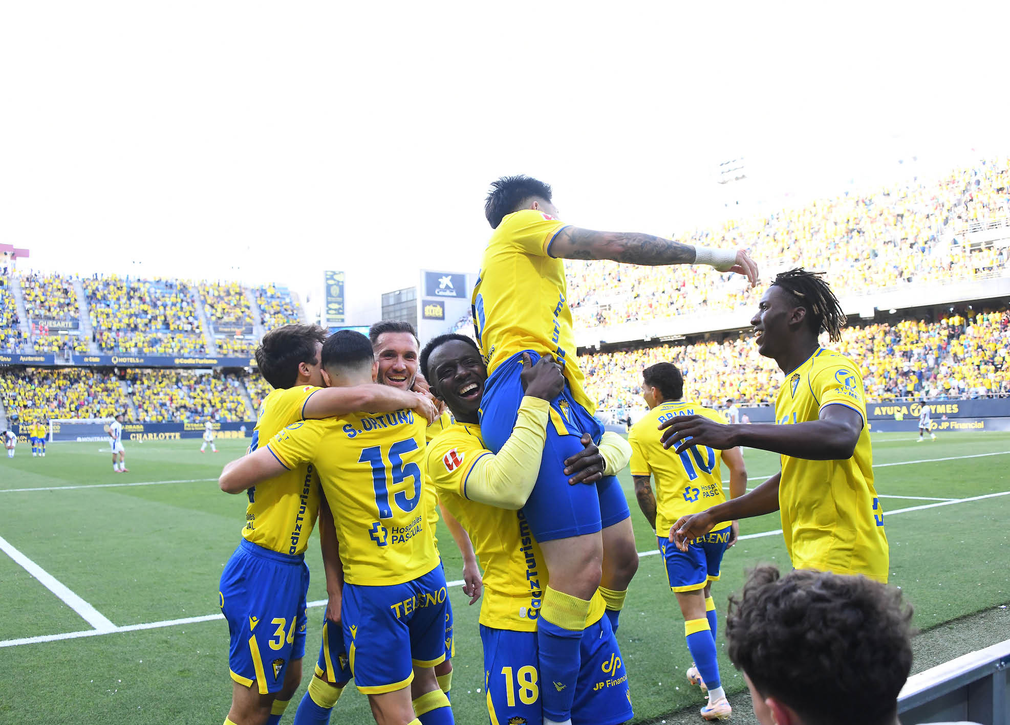 A group of soccer players in yellow and blue uniforms celebrating a victory. Descripci n generada con IA