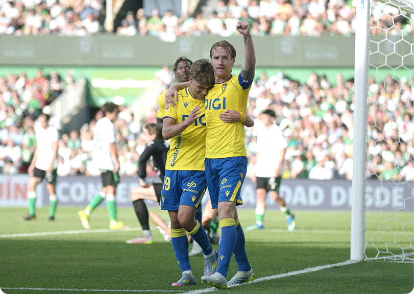 Two soccer players wearing blue and yellow shirts are hugging each other. Descripci n generada con IA