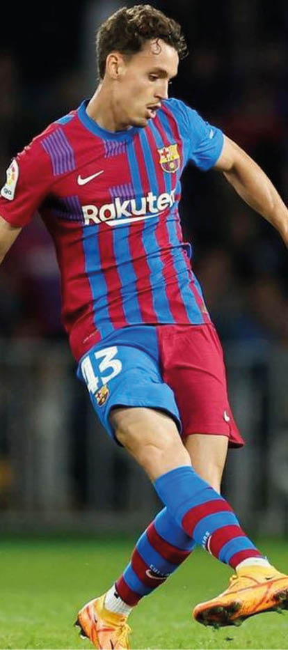 Un adulto con camiseta roja y parche de La Liga en la manga extiende el brazo derecho con el pu o cerrado. Descripci n generada con IA