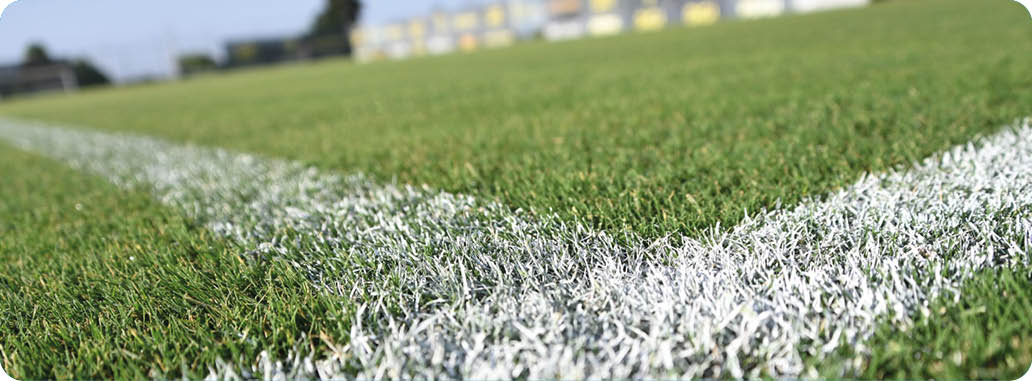 Campo de c sped con l neas blancas marcando las reas de juego, visto desde un  ngulo bajo.  Descripci n generada con IA