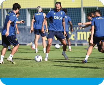 Personas vestidas con ropa deportiva azul juegan al f tbol en un campo de c sped durante un entrenamiento. Descripci n generada con IA
