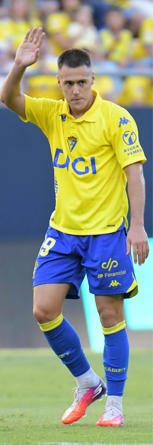 Persona con camiseta deportiva amarilla con logos y texto azul en un entorno que parece un evento deportivo. Descripci n generada con IA
