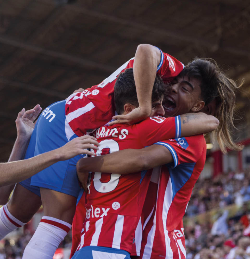 Personas con uniformes deportivos rojos y blancos celebran abraz ndose con entusiasmo en un estadio lleno de espectadores. Descripci n generada con IA