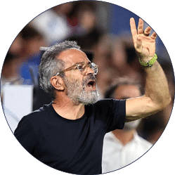 Una persona con gafas y camiseta negra est gesticulando y hablando en un entorno que parece un evento deportivo o p blico.  Descripci n generada con IA