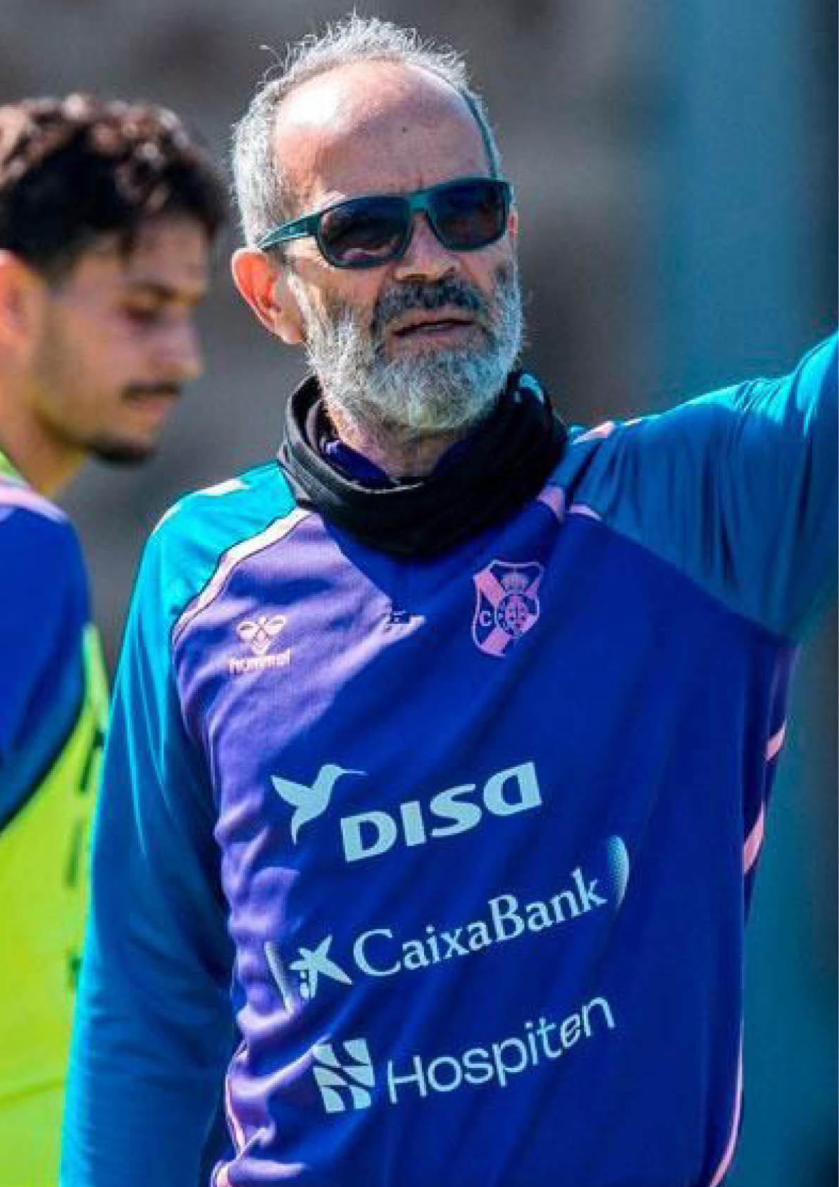 Una persona con camiseta azul y chaleco amarillo est cerca de una porter a de f tbol.  Descripci n generada con IA