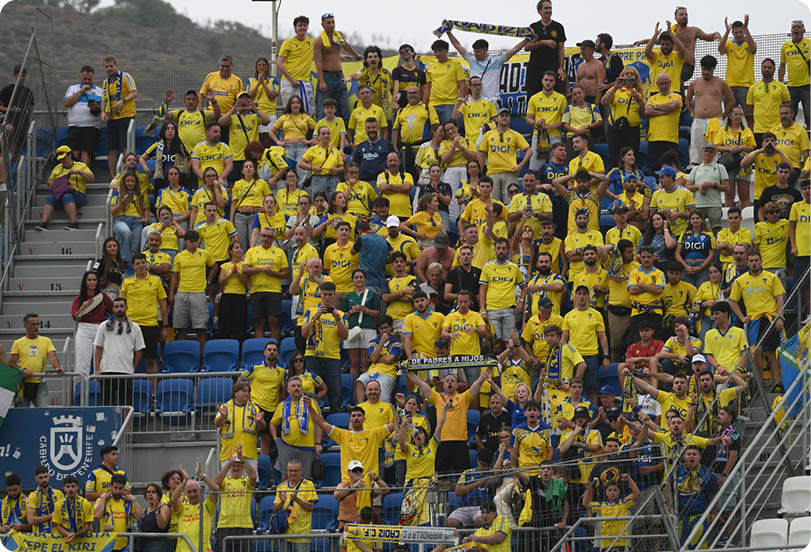 A large crowd of people wearing yellow shirts enthusiastically cheering and celebrating in stadium bleachers. Descripci n generada con IA