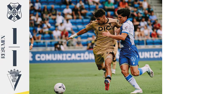 Two adults in sports uniforms are competing for a soccer ball on a field with spectators in the background. Descripci n generada con IA