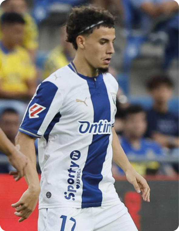 Dos personas con uniformes deportivos est n en un campo de f tbol durante un partido, una con camiseta amarilla y otra con camiseta blanca y azul. Descripci n generada con IA