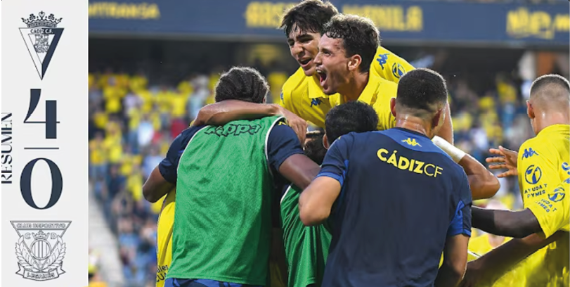 A group of athletes in yellow and blue uniforms are celebrating together on a sports field while a crowd in matching colors cheers behind them. Descripci n generada con IA